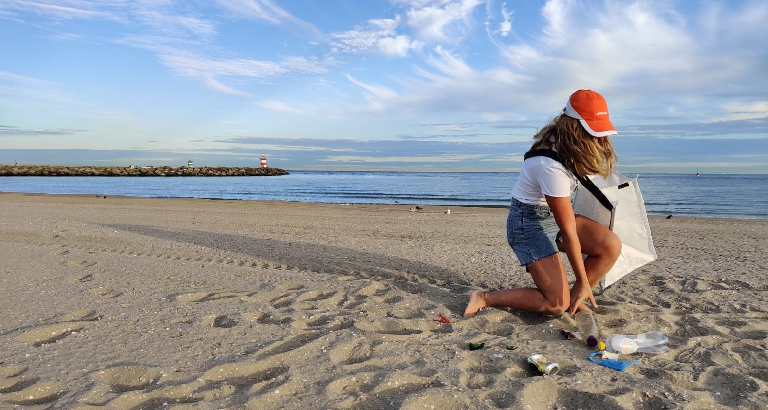 Volunteer picking up litter on the beach with a 123BigBags clean-up bag
